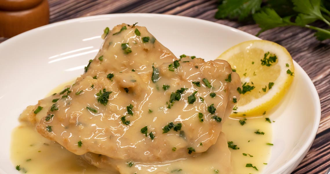 Chicken Francese with capers on a white plate