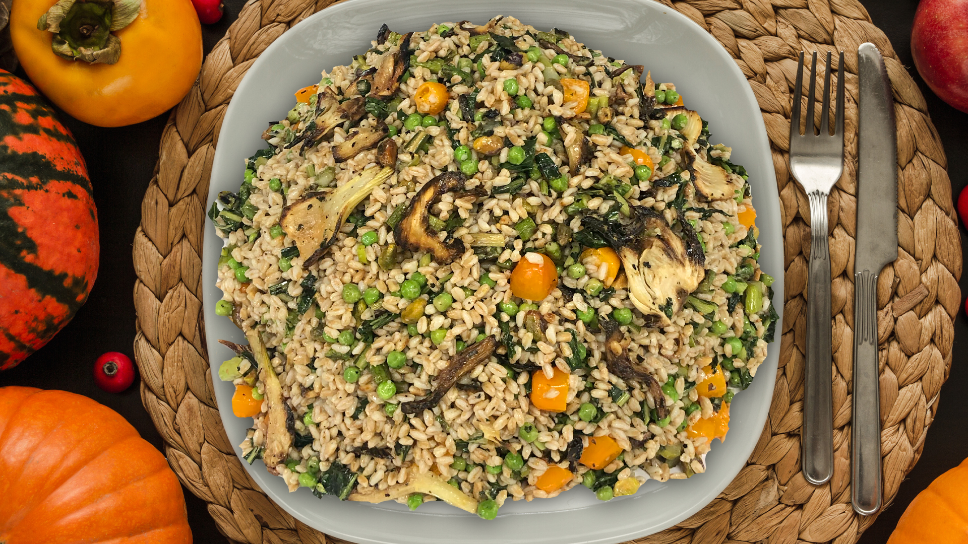 Fall Farro salad on a white plate with a brown placemat surrounded by squashes