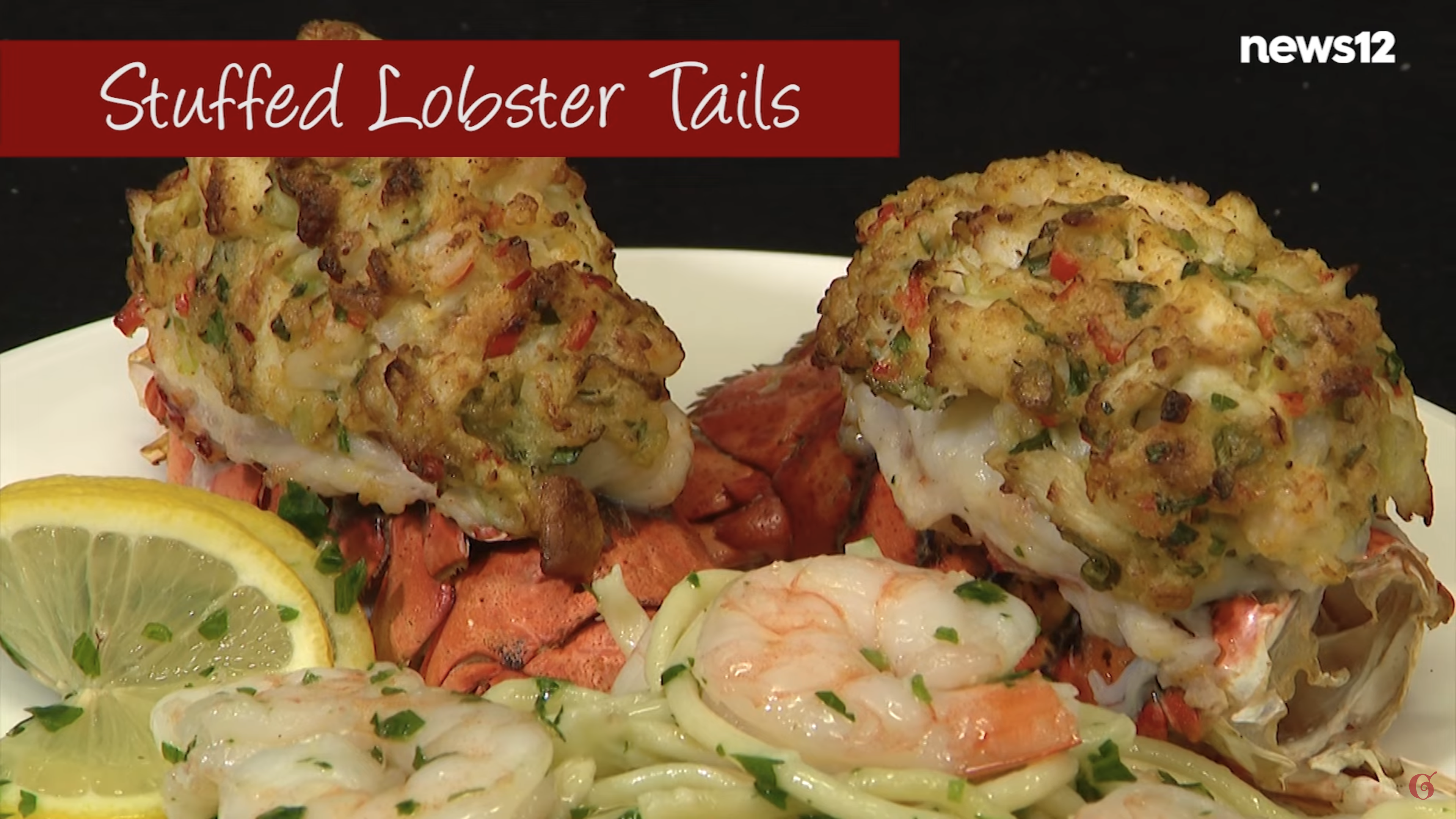 Stuffed lobster tails on a plate with pasta, shrimp and a lemon